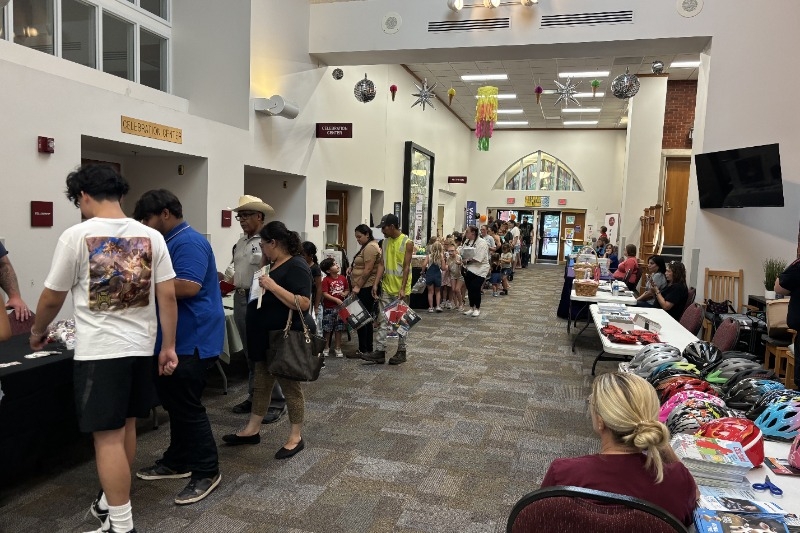 Looking down a hallway full of people and tables filled with stuff for families