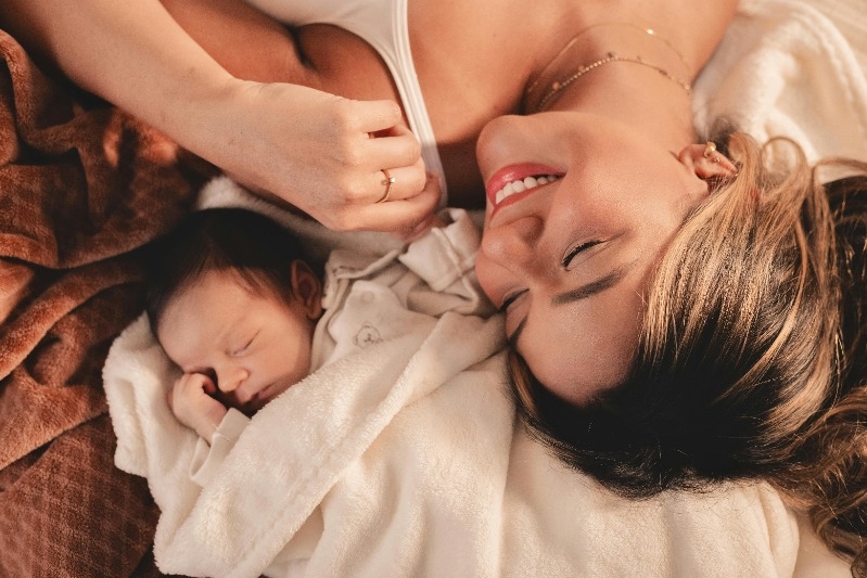 Mother is smiling while laying beside her newborn baby